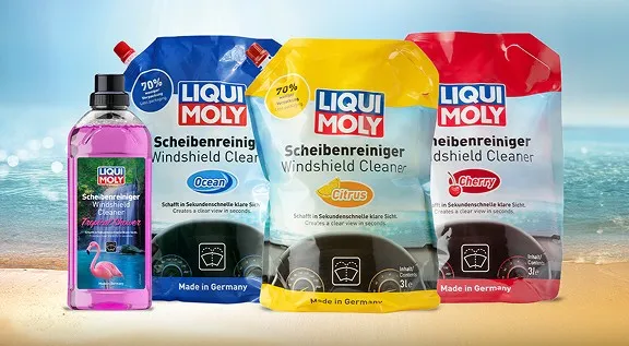 Vier sommerliche Liqui Moly Scheibenreiniger-Produkte vor einem sonnigen Sandstrand und Meer.