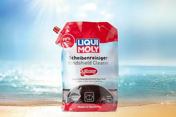 Roter Liqui Moly Beutel für Scheibenreiniger mit Kirsch-Duft vor einem hellen Sandstrand.